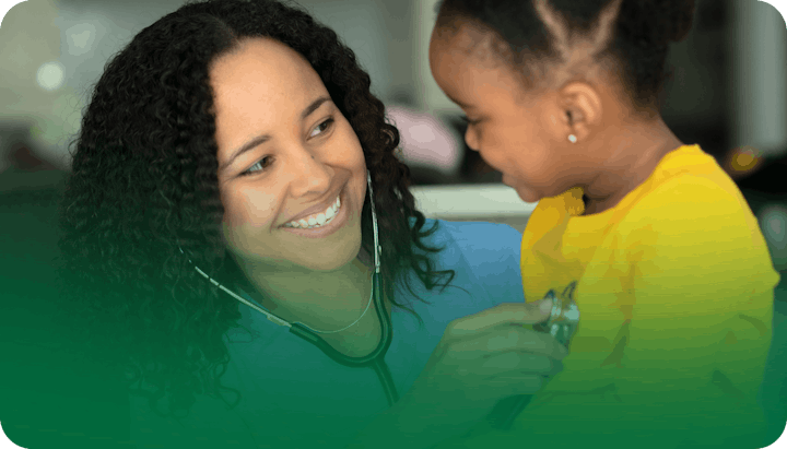 A smiling healthcare professional uses a stethoscope on a happy child wearing a yellow shirt.