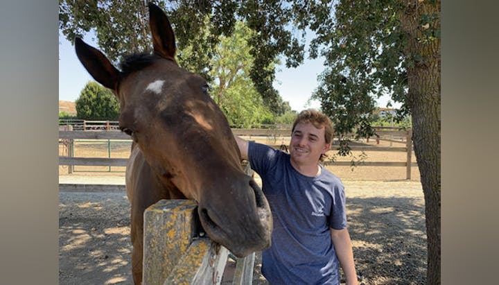 smiling person petting a horse