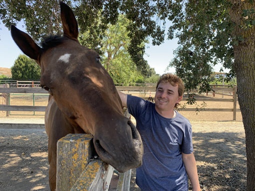 smiling person petting a horse