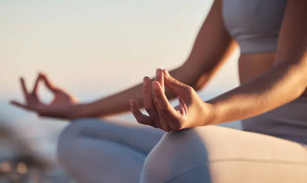A person meditating in a serene setting, with hands positioned in a mudra, promoting relaxation and mindfulness.