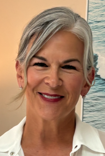 A person smiling, wearing a white shirt, with gray hair styled neatly. The background features an abstract pattern with blue tones.
