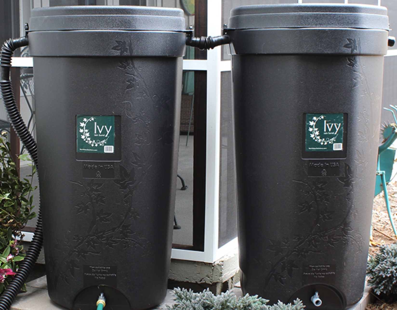 Two identical rain barrels with attached hoses and floral design.