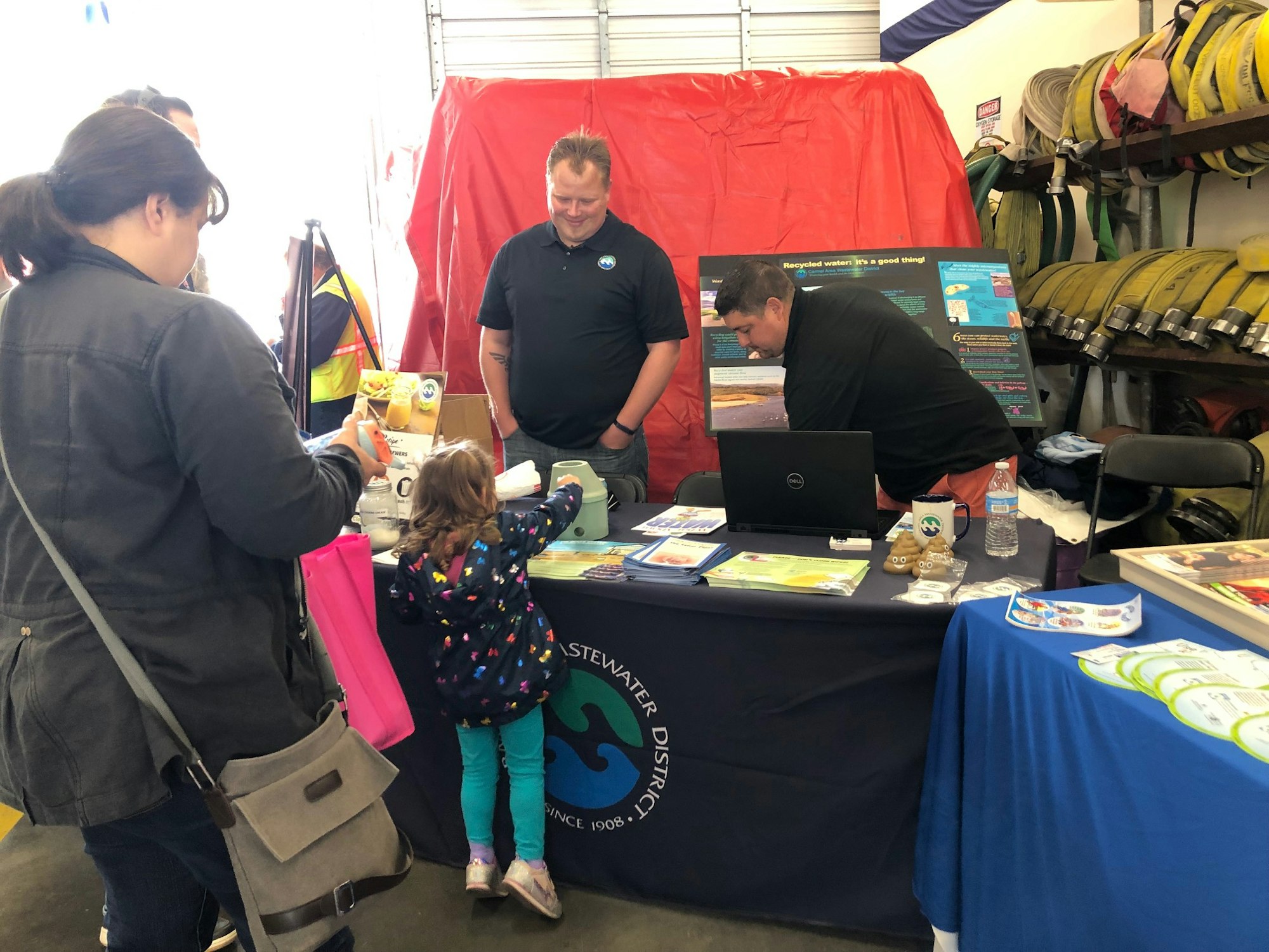2019.07.20 Community Engagement-Safety Week-table set up with wastewater treatment flyers. Image shows youth and adults at the table.