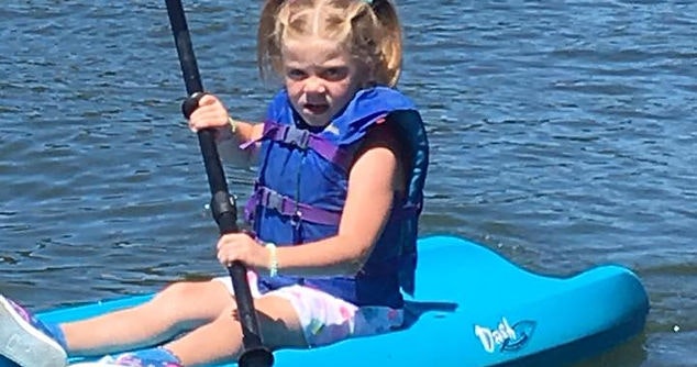 A child in a life jacket kayaking on the water.