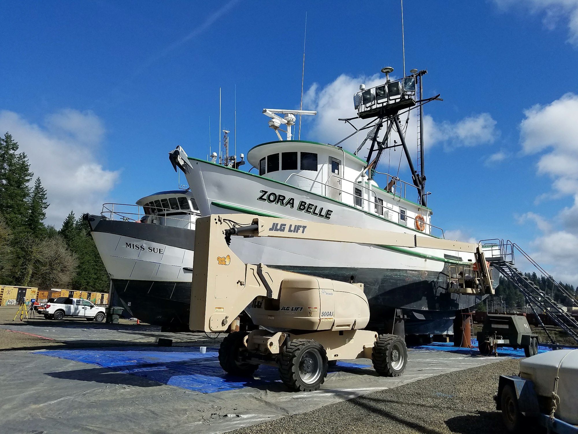 A fishing boat named "Zora Belle" in a dry dock with clear skies in the background.