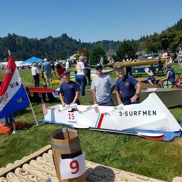 People at an outdoor event with boats and flags.