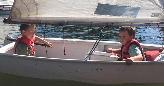 Two children in life jackets on a sailboat.