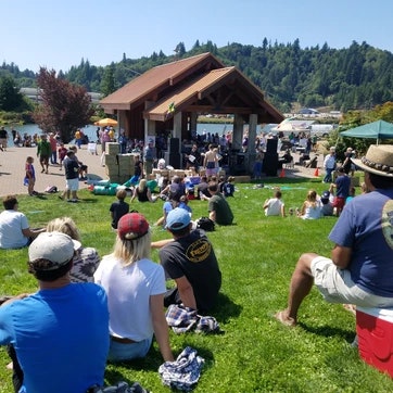People enjoying an outdoor event with live music at a park on a sunny day.