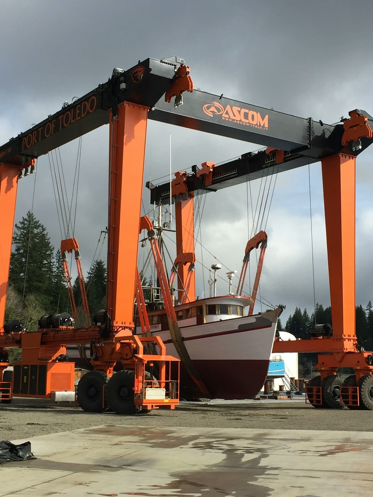 A boat being lifted by a large orange gantry crane at Port of Toledo.