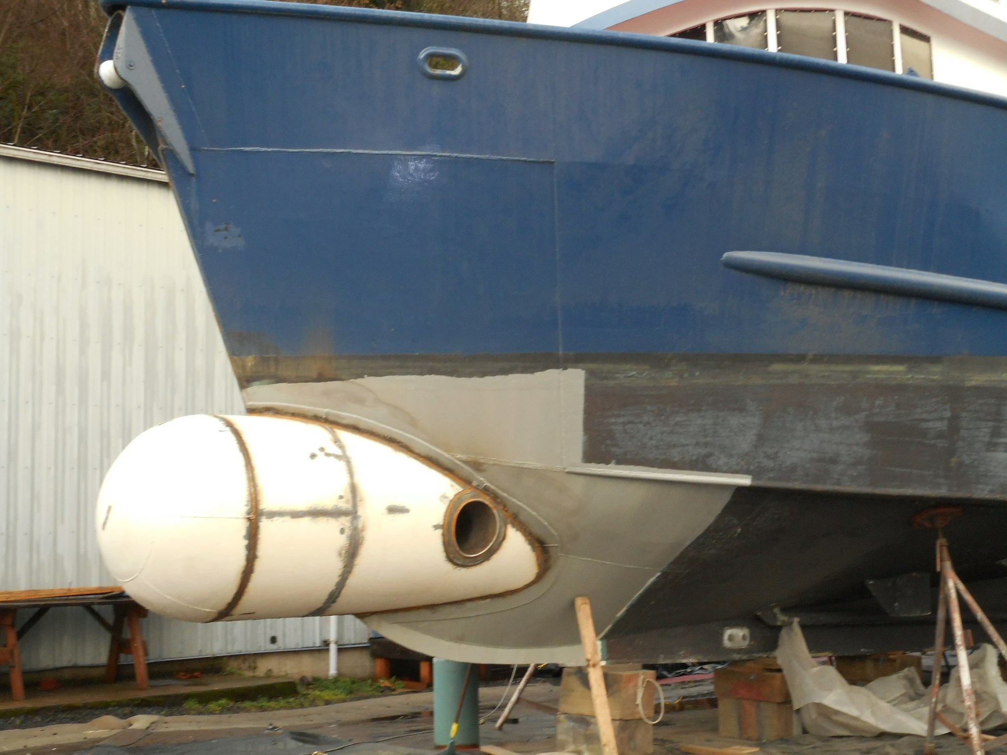 Blue boat on land with bulbous bow visible.