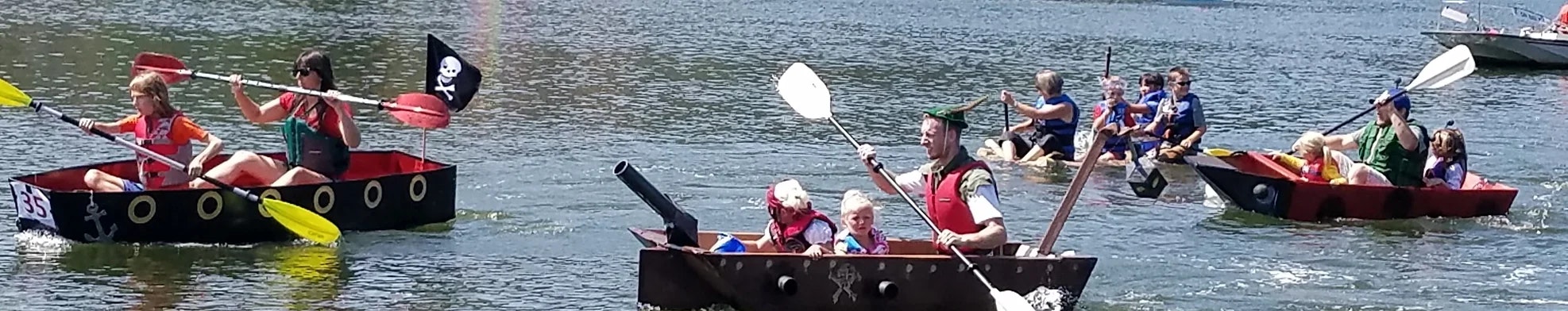 Boats with pirate-themed decorations and people paddling on water.