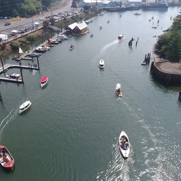 Aerial view of a river with boats, some piers and buildings along the shore.