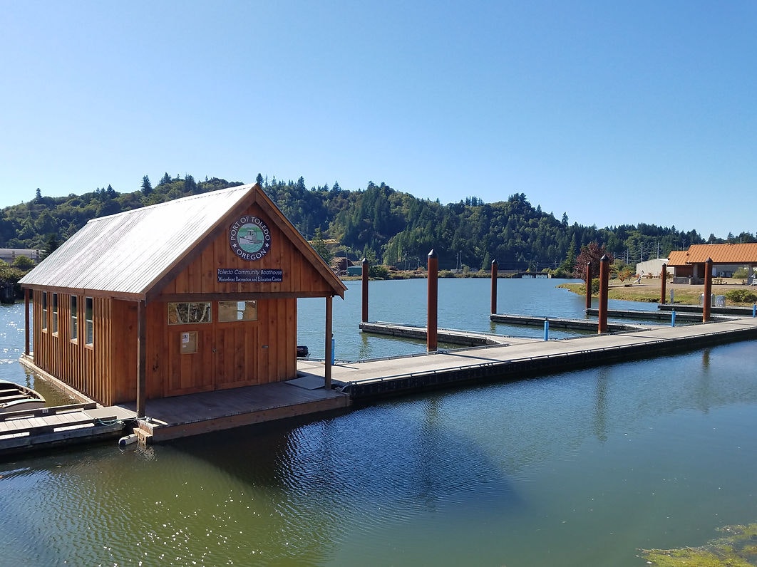 A wooden boathouse on a dock with clear skies and hills in the background.