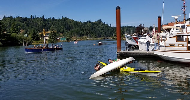 Boats on water, capsized kayak, people, sunny day.