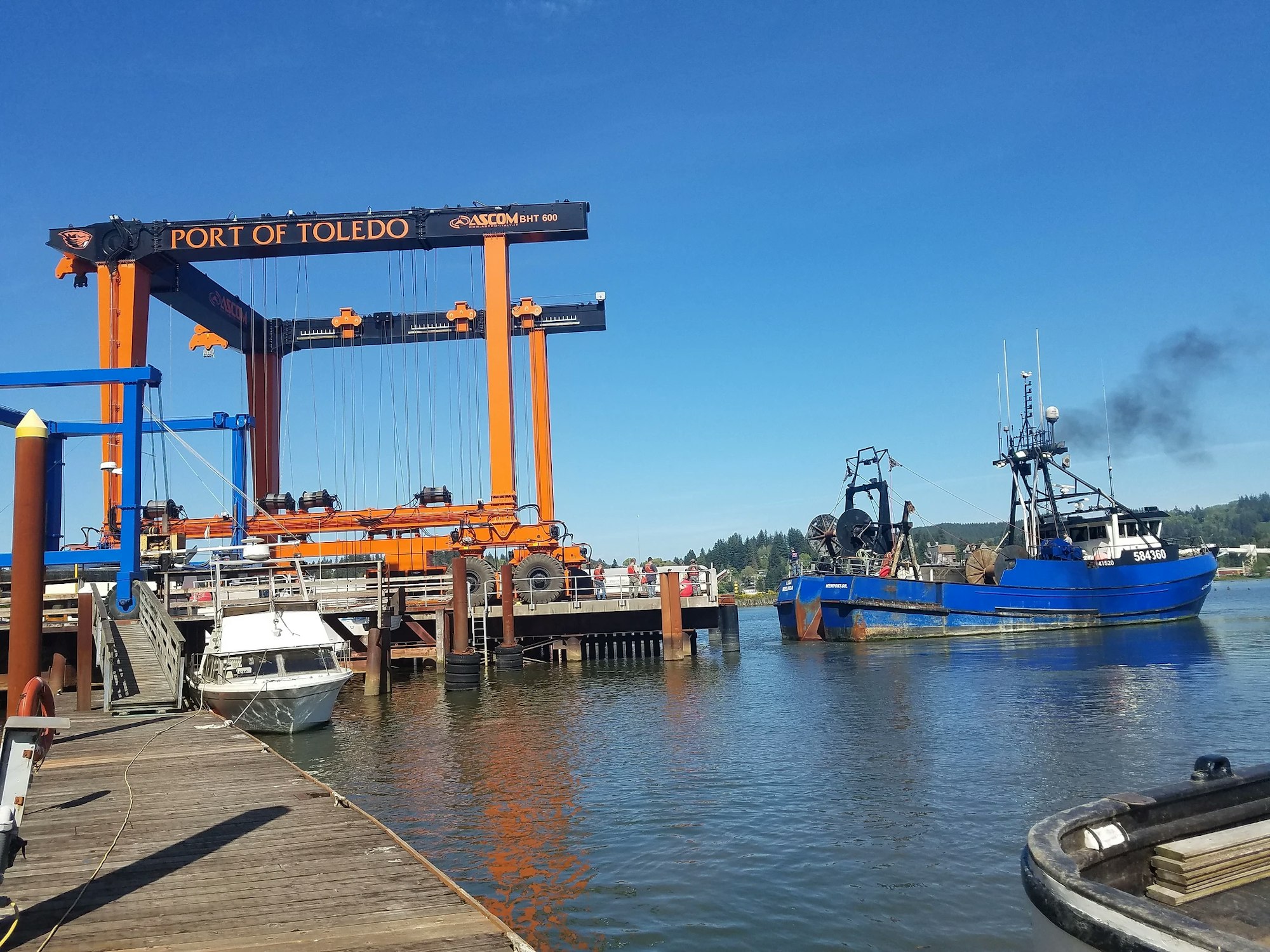 A boat is docked at a sunny Port of Toledo beside a large orange boat lift.