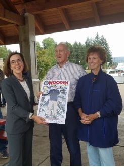 Three people posing with a certificate or award outdoors.