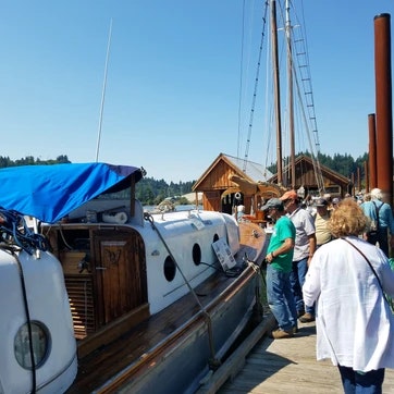A dockside scene with people amid boats on a sunny day.