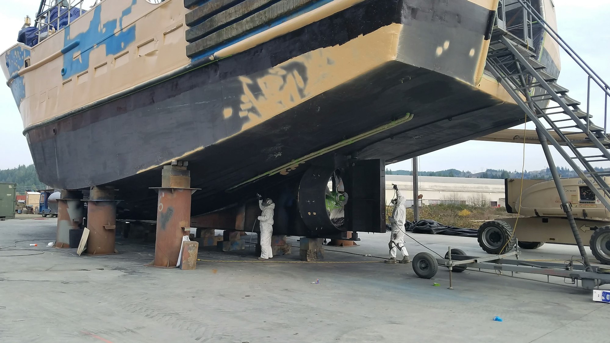 A ship on dry dock being worked on by people in protective gear.