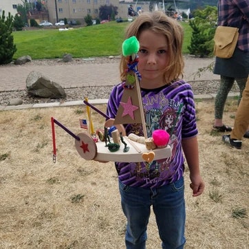 A child holding a homemade craft with colorful decorations.