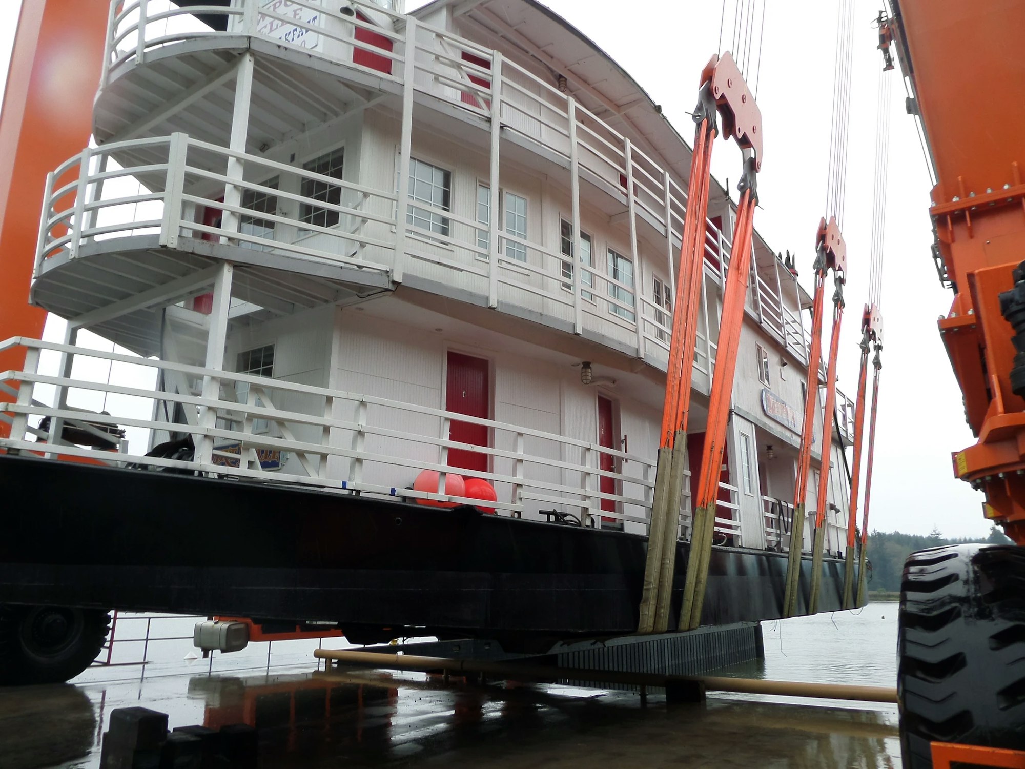 Partial view of a boat with a crane alongside it, possibly during maintenance or construction.