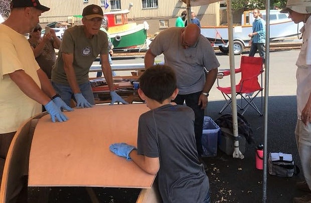 People at an outdoor event, one wearing gloves at a table, others standing around.
