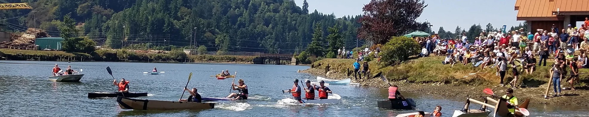 A boat race on a river with spectators watching from the shore.