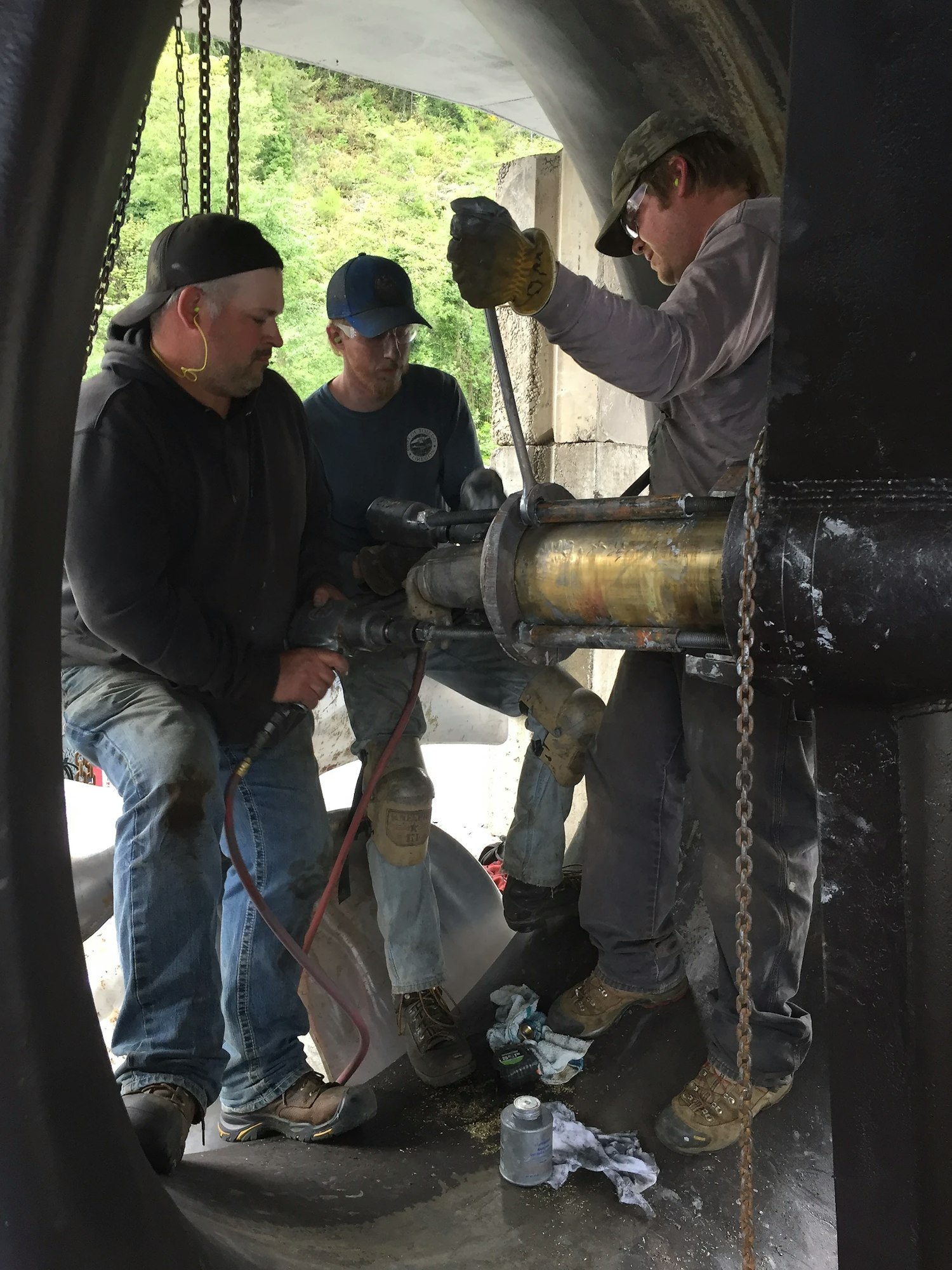 Three men working on a pipe, possibly maintenance or construction.