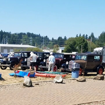 Outdoor vintage car show with people viewing classic cars on a sunny day.