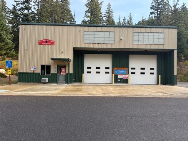 Building with two garage doors, signs, and surrounded by trees.
