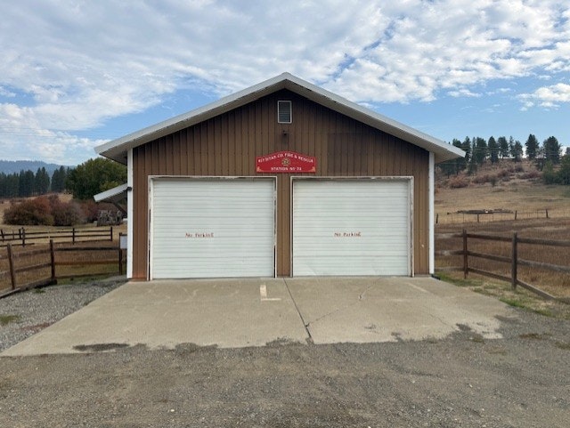 A small brown building with two garage doors labeled "No Parking," set in a rural landscape with cloudy skies.