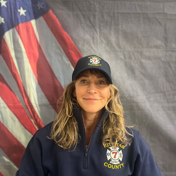 A person in a Kittitas County Fire District 7 uniform is posing in front of an American flag.