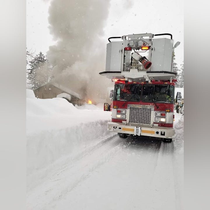 Fire truck responding to a building fire in snowy conditions, with flames and smoke visible.