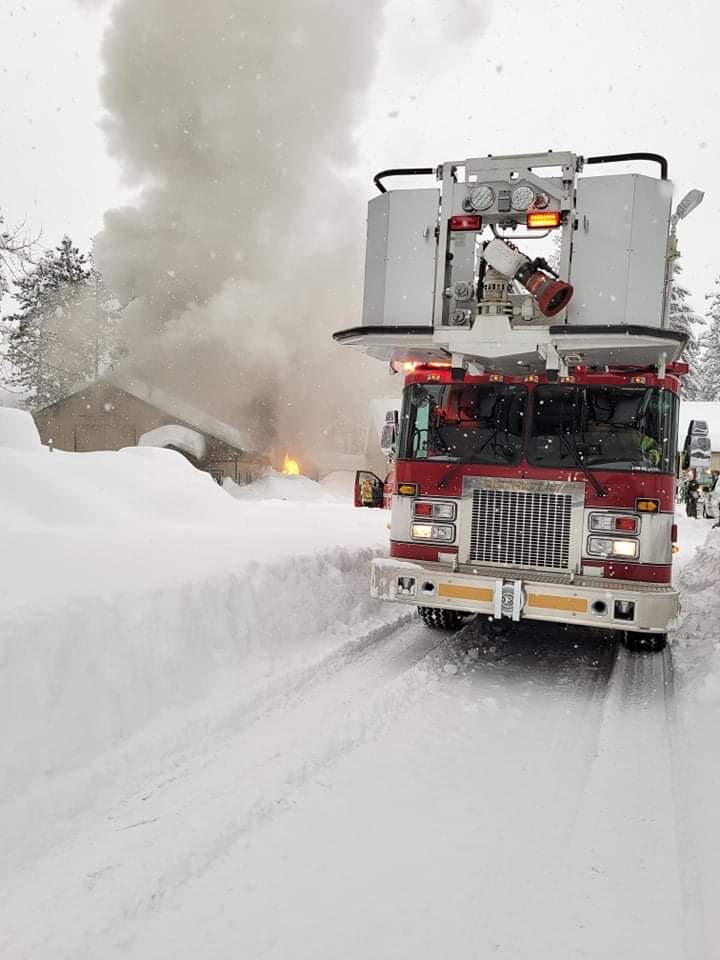 Fire truck responding to a building fire in snowy conditions, with flames and smoke visible.