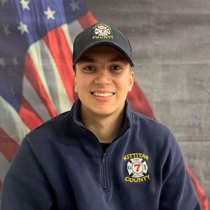 Person in Kittitas County fire department apparel, U.S. flag background.