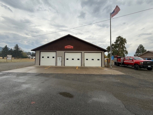 A small fire station with three garage doors, an American flag, and a red truck parked outside.
