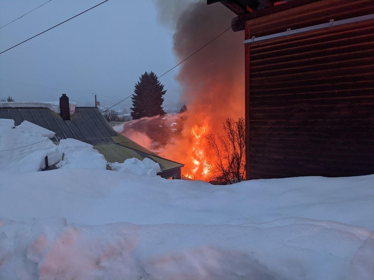 A building surrounded by snow is on fire, with flames and smoke visible.
