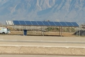 A solar panel array next to a road with mountains in the background.