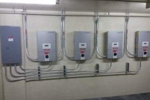 Five electrical panels with organized conduit piping on a wall.