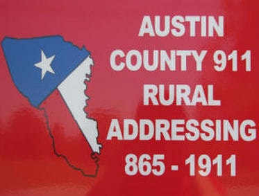 A sign for Austin County 911 Rural Addressing with a map graphic and contact number.