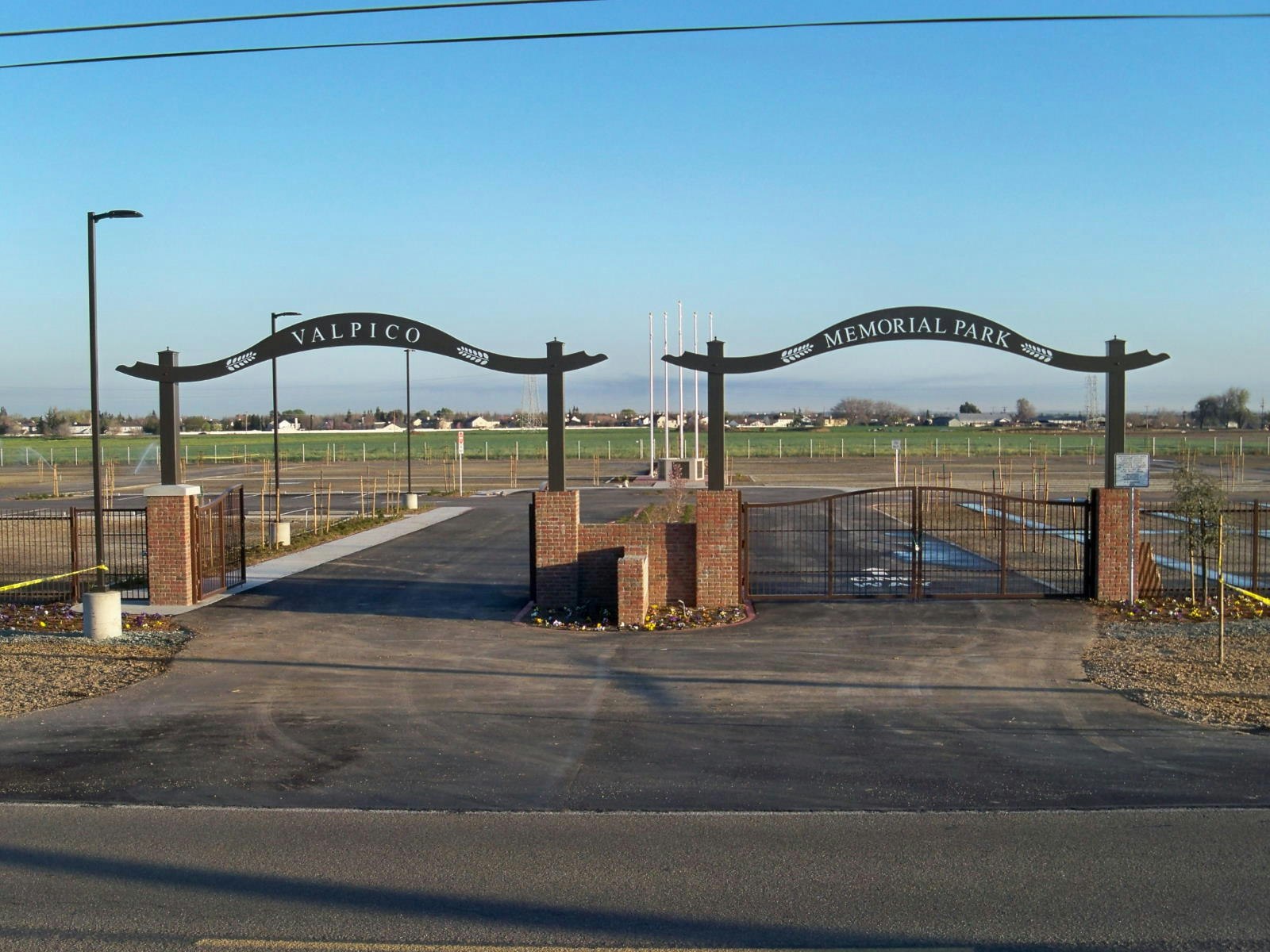 Entrance gate of Valpico Memorial Park with fields and a clear blue sky in the background.