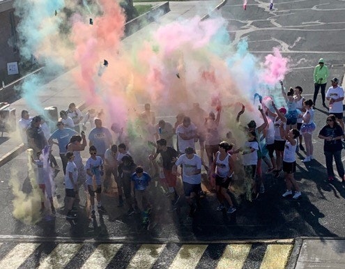 Participants celebrating in a colorful cloud of powder at an outdoor event, likely a fun run or festival.