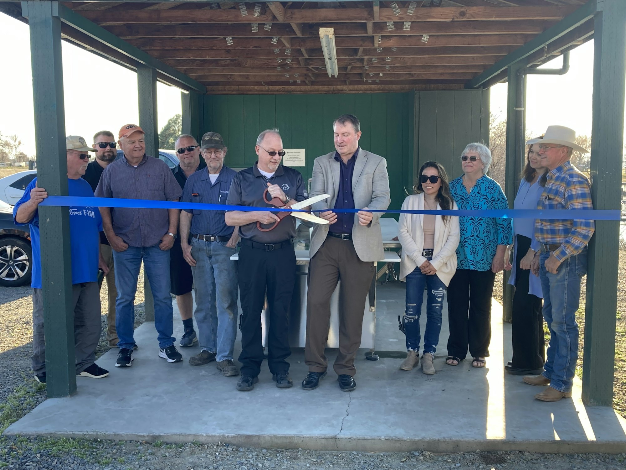 Group of people participating in a ribbon-cutting ceremony.