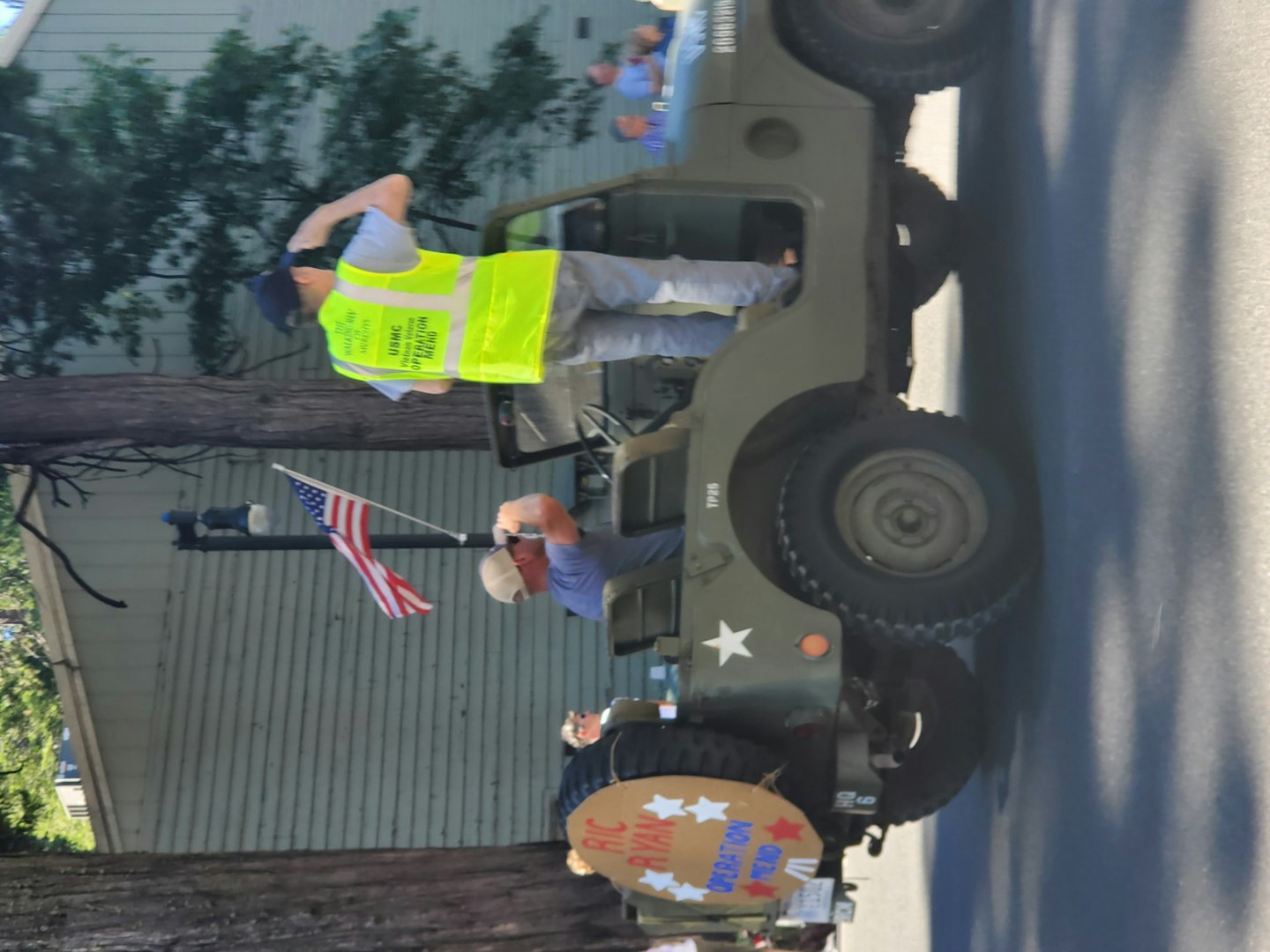 May contain: flag, clothing, hardhat, helmet, person, adult, male, man, hat, vest, car, transportation, and vehicle