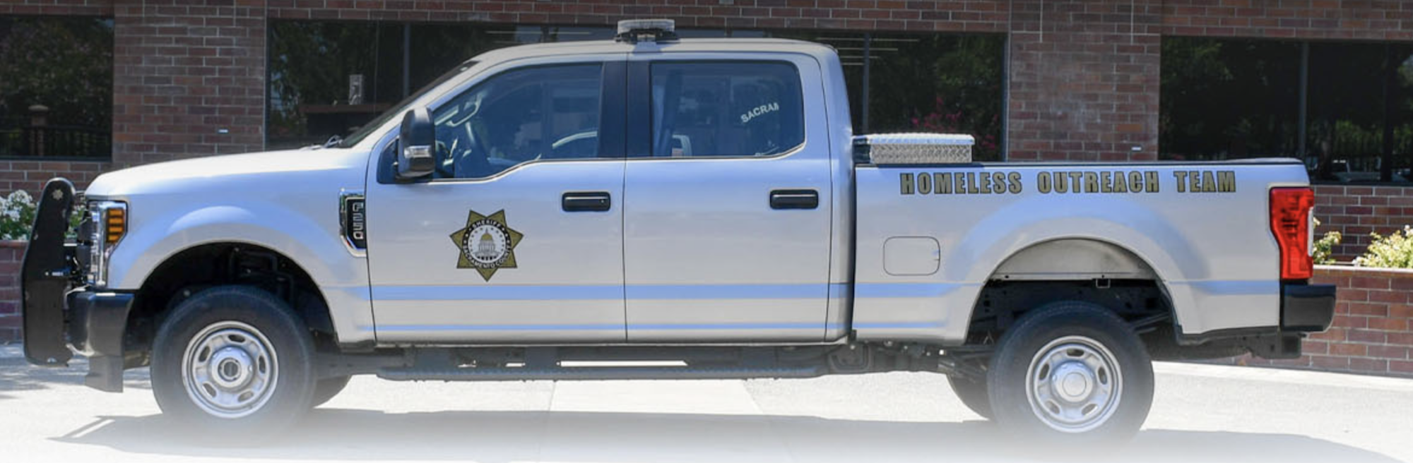 A white pickup truck labeled "Homeless Outreach Team" with a badge on the door.