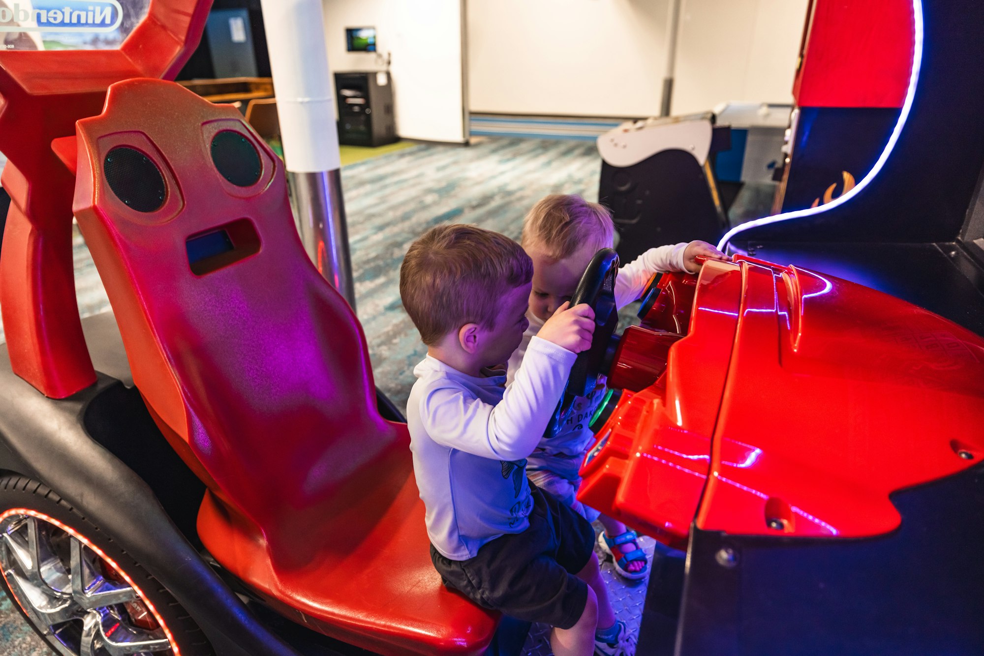 Two children are playing with a coin-operated ride game at an arcade.