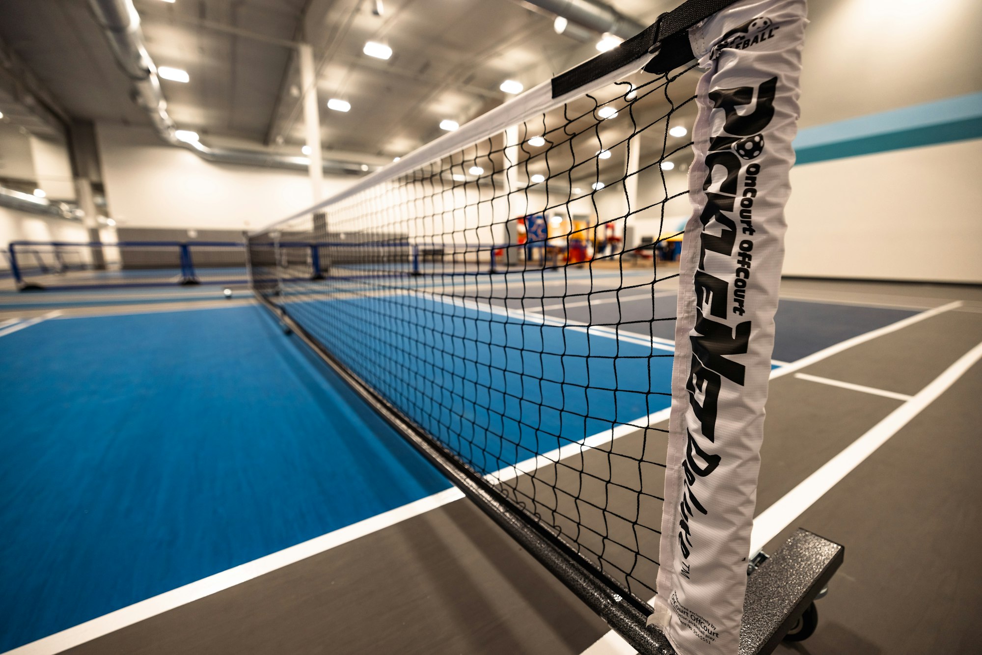 Indoor pickleball court with a close-up of the net and court lines.