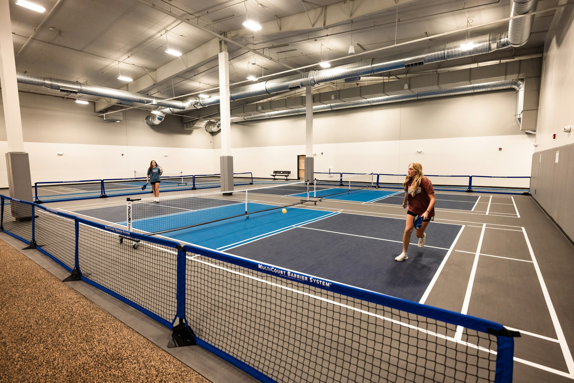 Indoor pickleball courts with players.