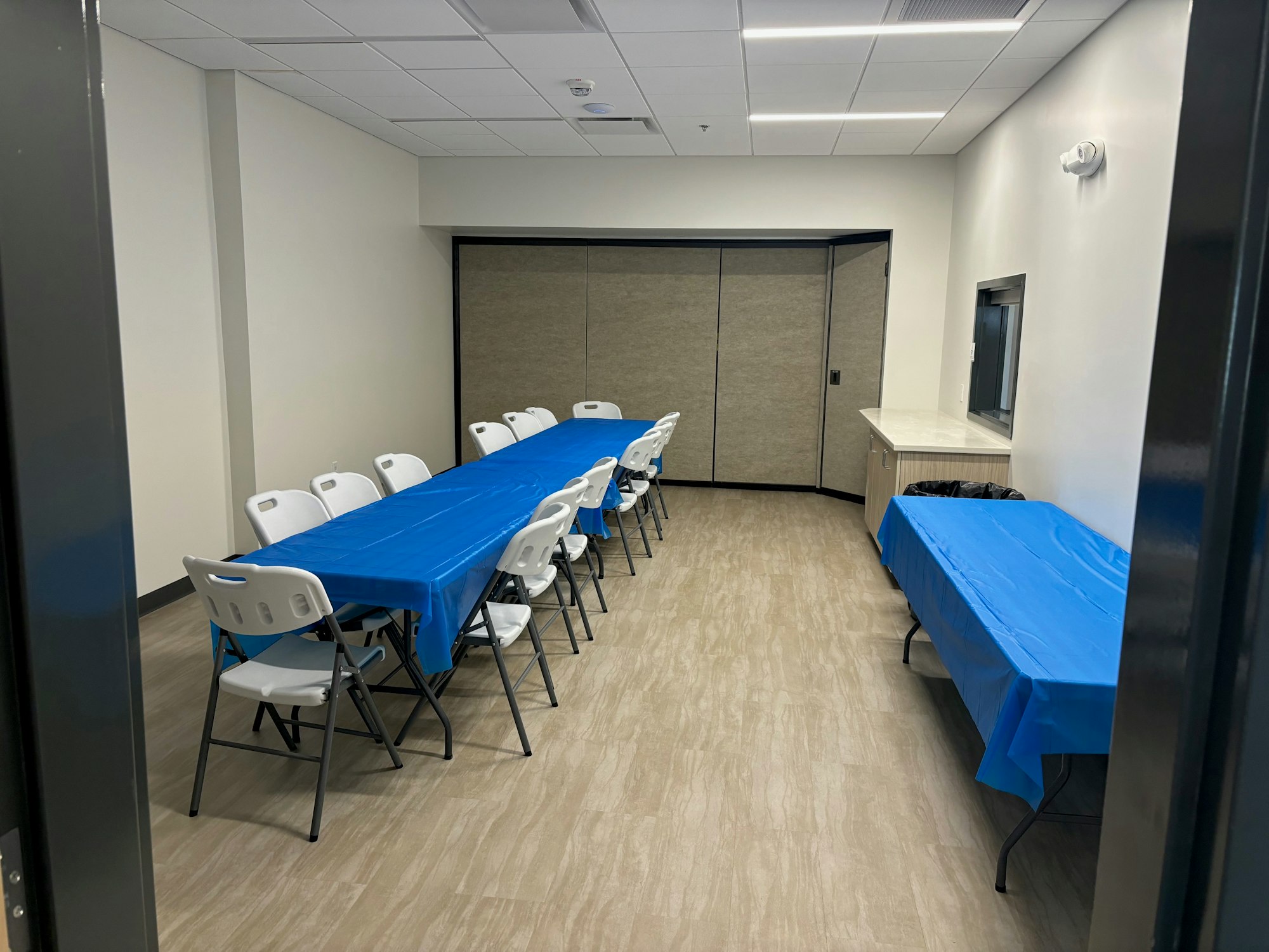 A modern room with tables covered in blue cloths, chairs, and a counter.