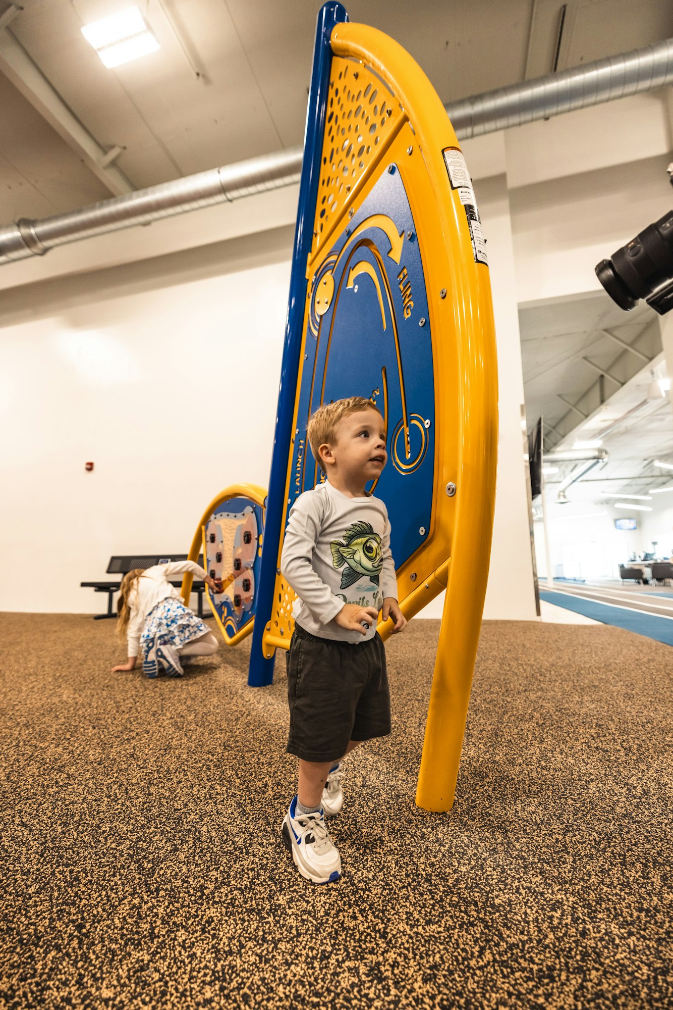 A child playing with a large, colorful music-making installation indoors.