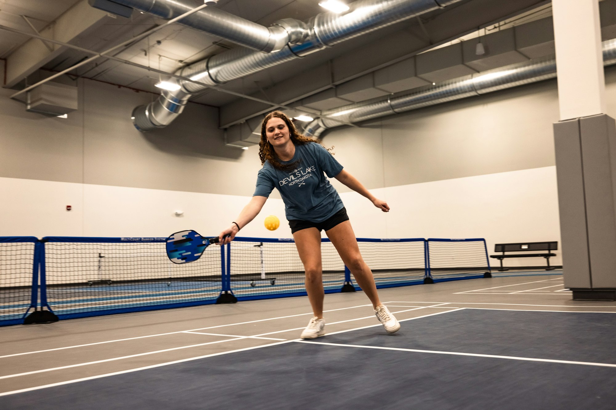 Person playing pickleball indoors.